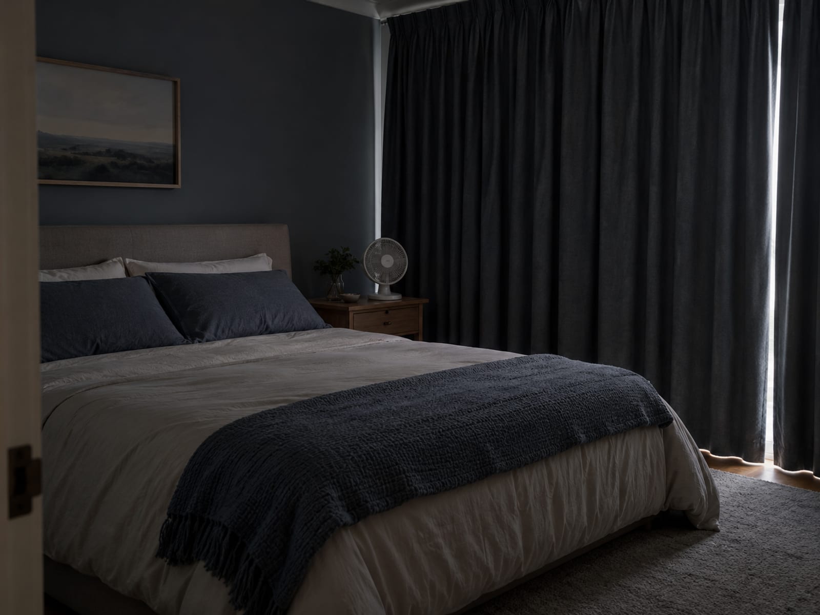 A dim, tidy bedroom with the curtains drawn